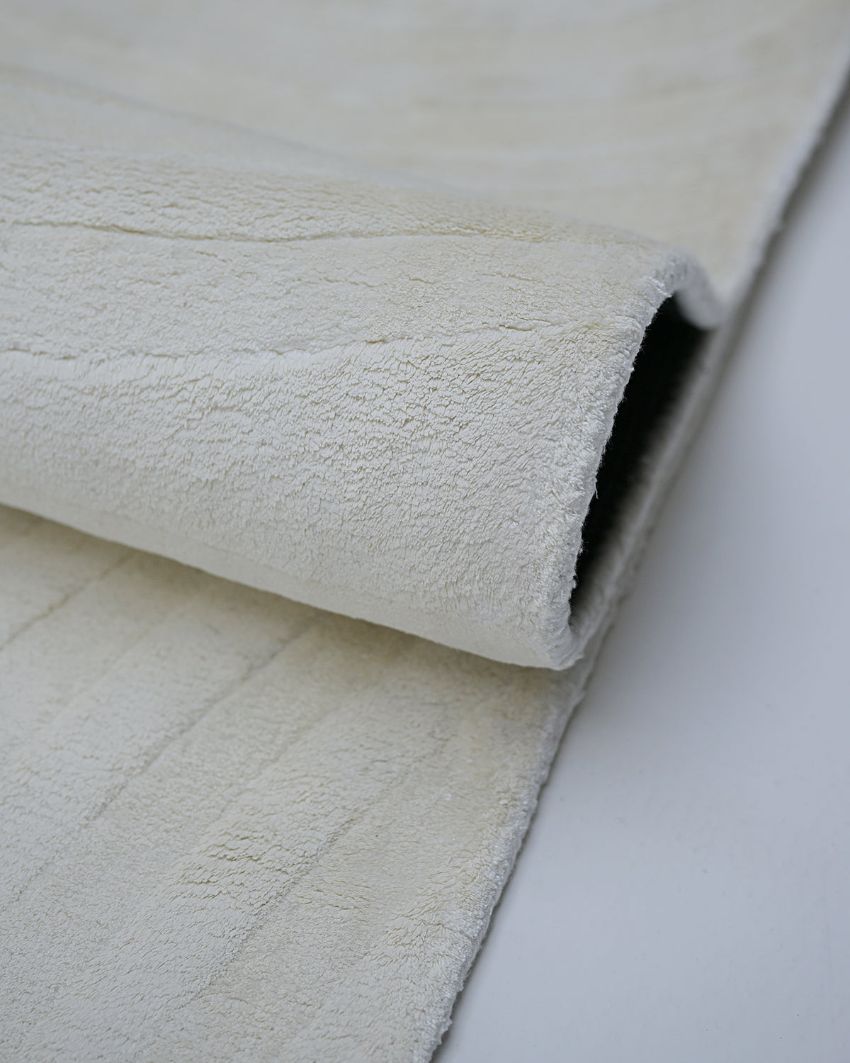 Ivory white hand-tufted bamboo silk rug fold and pile detail