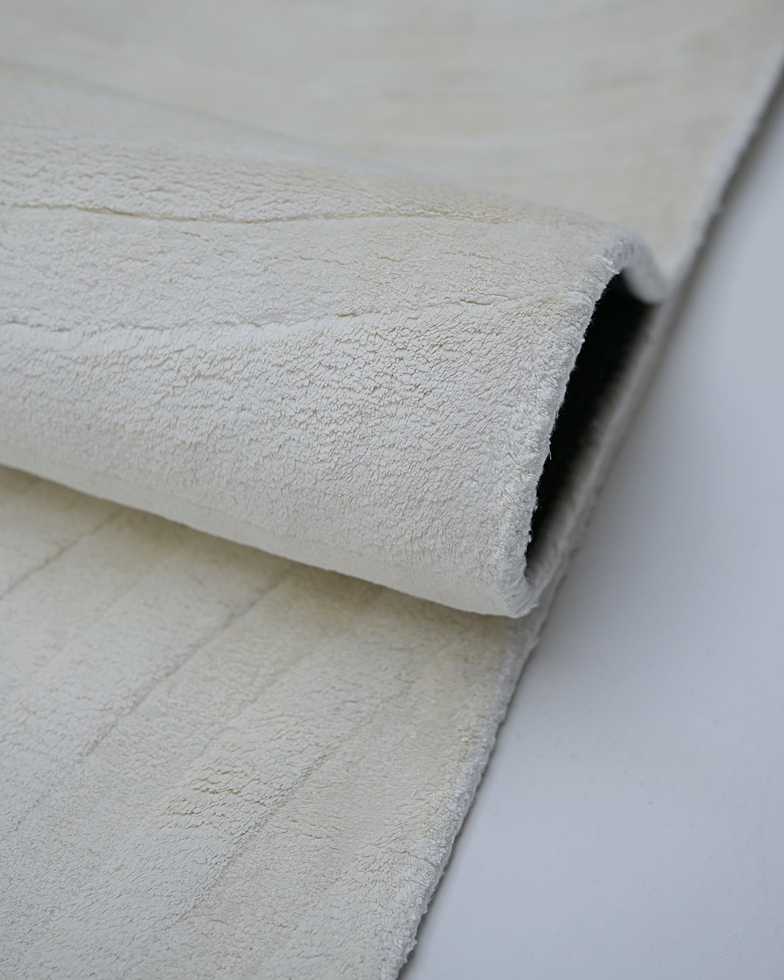 Ivory white hand-tufted bamboo silk rug fold and pile detail